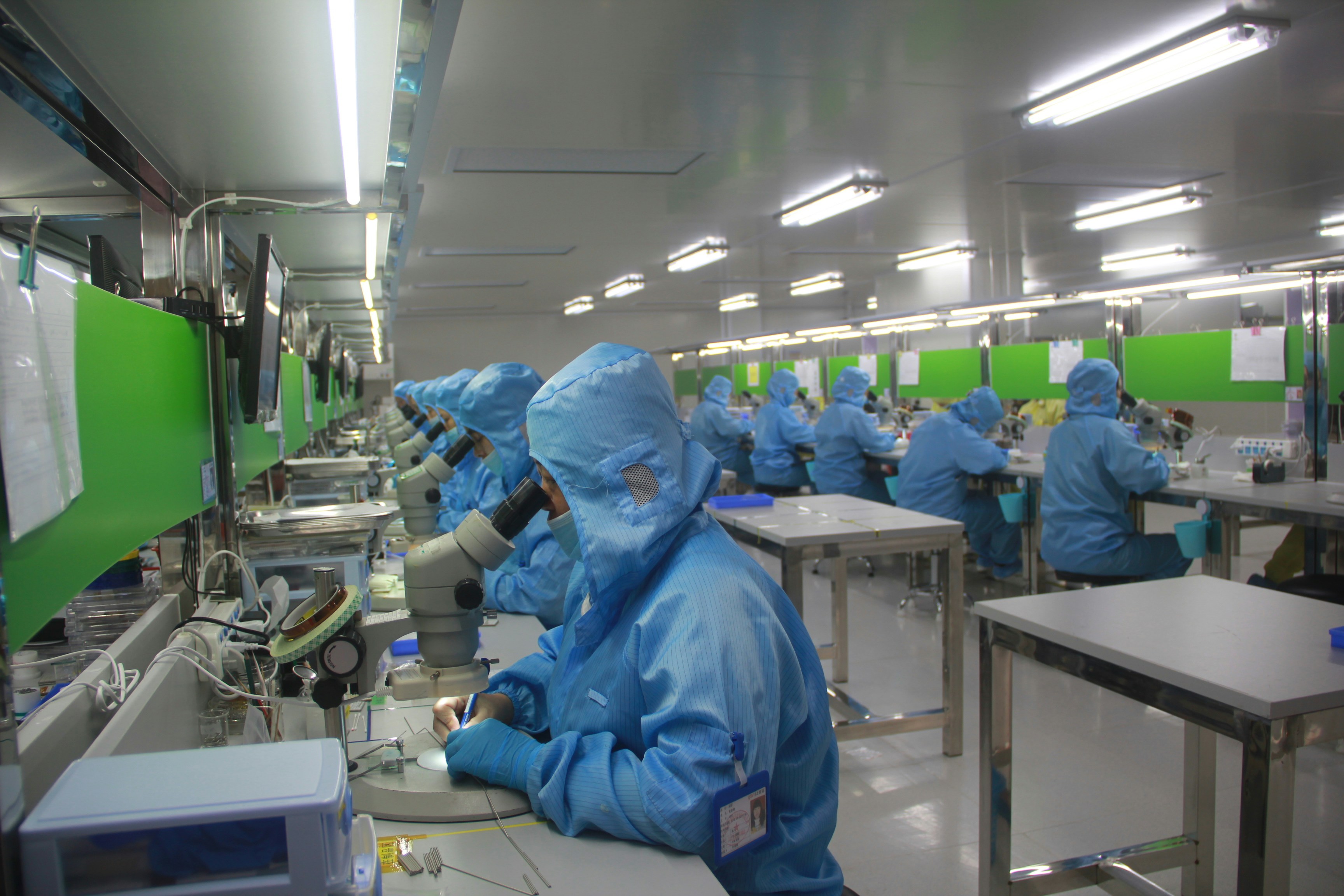 Modern manufacturing facility with automated production lines, industrial robots, quality control stations, clean factory environment